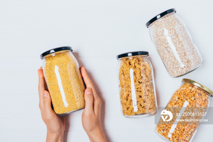 Woman’s hands holding glass jar of millet