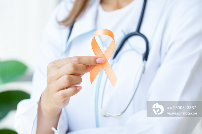 Close up of a doctor holding and showing orange awareness ribbon in her hands