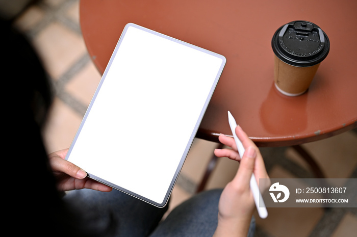 An Asian woman using digital tablet, working on her project, sitting at outdoor table