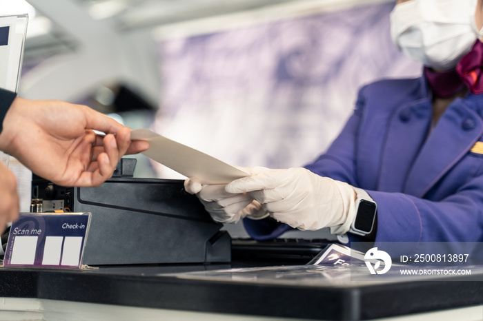 Asian female traveler wearing mask give passport to check in counter.