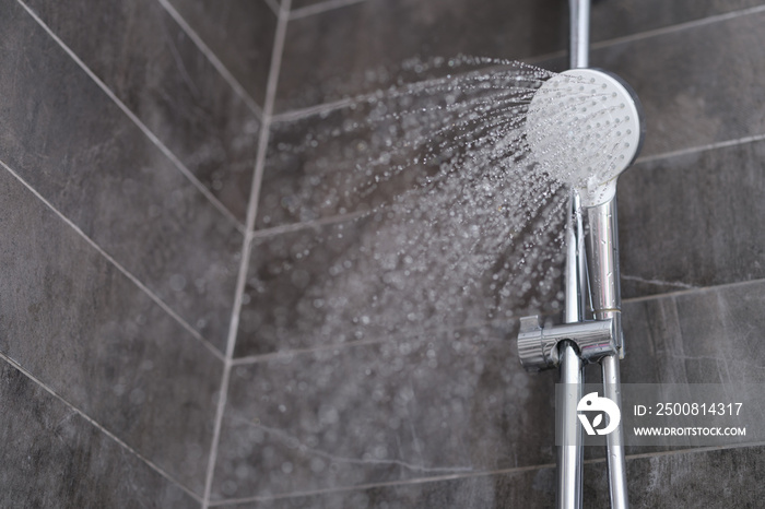 Trickles of water flowing from shower head in bathroom closeup