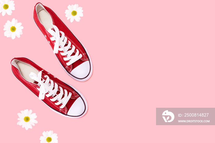 Red sneakers on pink background with flowers top view copy space - Spring and summer  shoes fashion concept