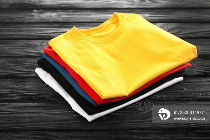 Stack of colorful t-shirts on wooden background