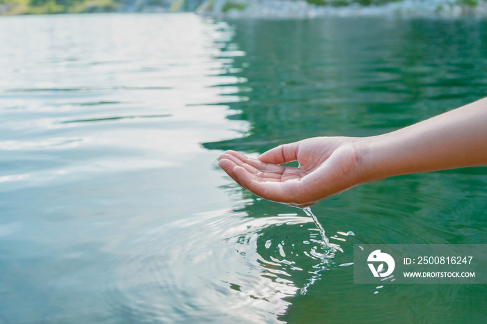 hand touches water in pond with sunshine