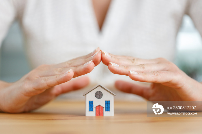 Miniature house covered by business woman hand tiny house. Home insurance, property insurance concept.