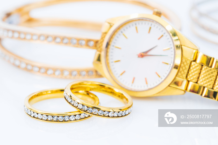 Luxury gold ring and lady gold watch on white