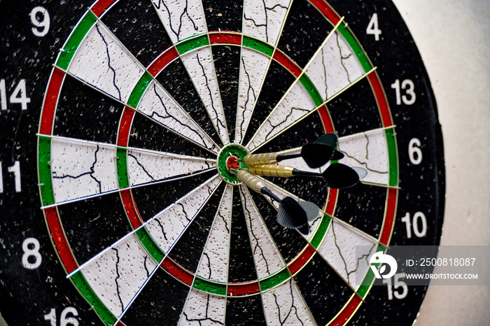 Three darts hit the center of the board while playing darts.