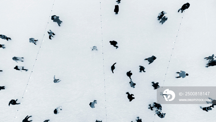 Top view of people skating on large open air ice rink on winter day. Aerial Drone View Flight Over crowd people skate on ice rink. Winter sport activities. Skating background. City Ice Rink Blue color