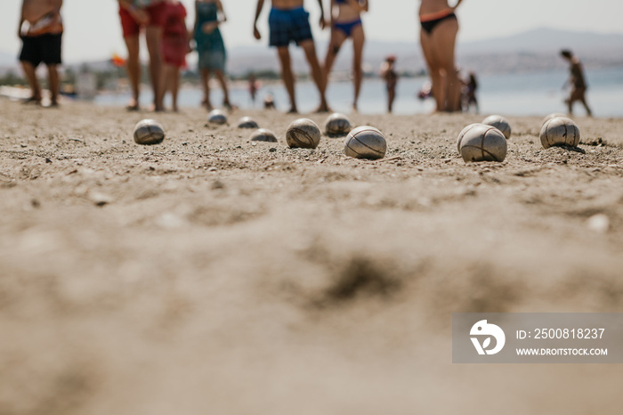 Beach holidays for tourists from all over Europe, they play an active game - petanque on a sandy beach by the sea