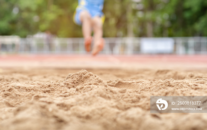 Boy athlete performing a long jump during a competition