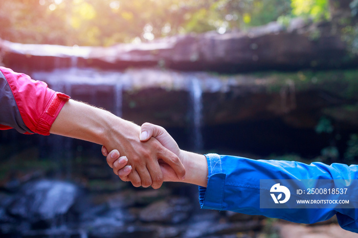 The climbers on the cliff pulled their hands together, two people helping each other.Two tourists shaking hands,Successful business people handshaking