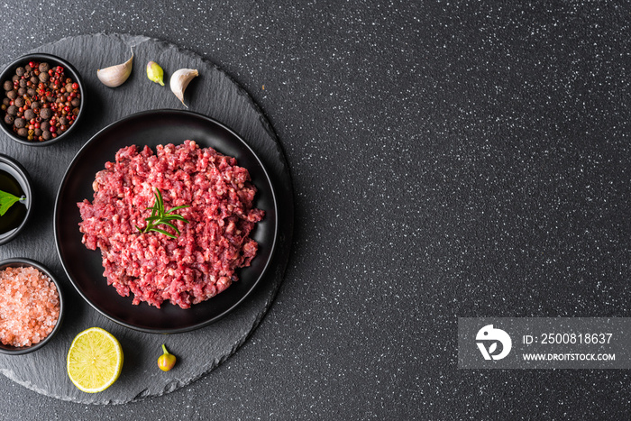 Fresh minced meat ground beef on a black plate against stone background