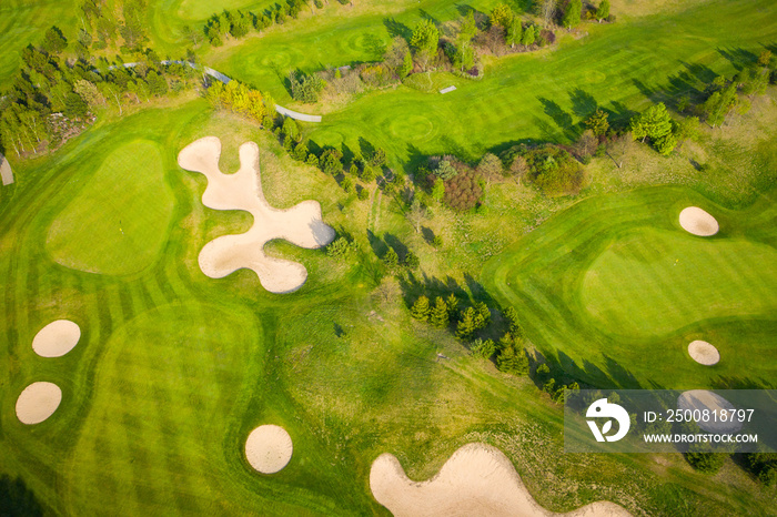 Aerial view of a golf course fairway and green with sand traps, trees and golfers.