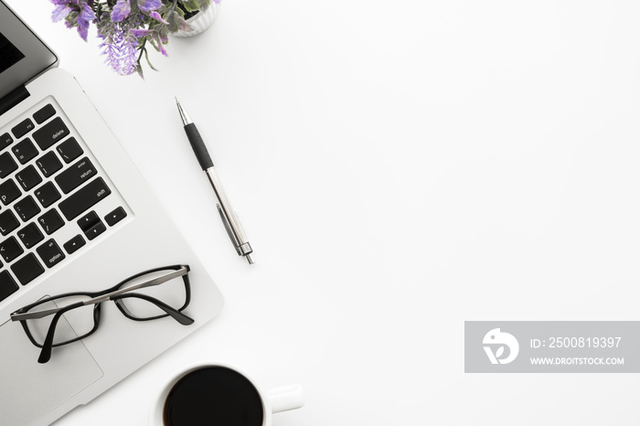 White office desk table with laptop computer, cup of coffee, pen, eye glasses and flower pot. Top view with copy space, flat lay.