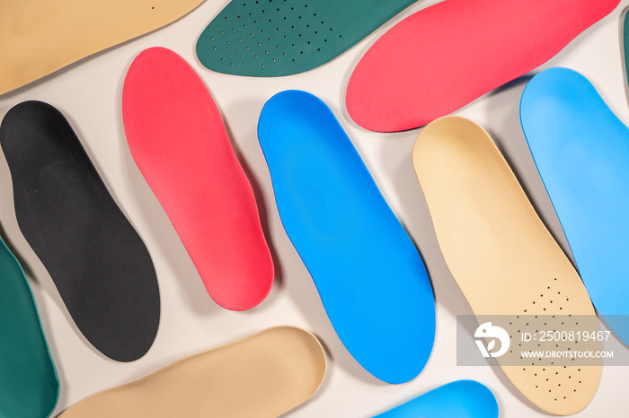 Orthopedic insoles are lined up on a wooden surface. samples of different orthopedic insoles. insoles with a variety of coating.