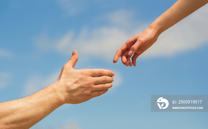 Giving a helping hand. Hands of man and woman on blue sky background. Lending a helping hand. Solidarity, compassion, and charity, rescue. Hands of man and woman reaching to each other, support