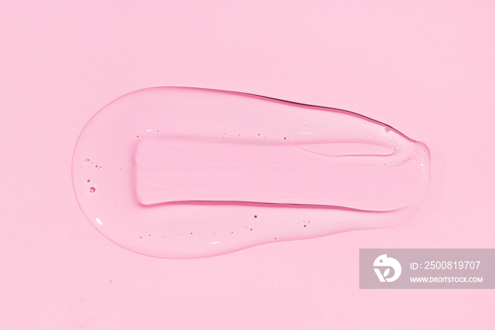 Liquid gel or beauty serum texture isolated on pink background. Transparent cosmetic skincare product. Close up