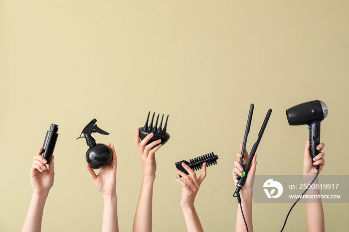 Many hands with hairdresser’s supplies on color background