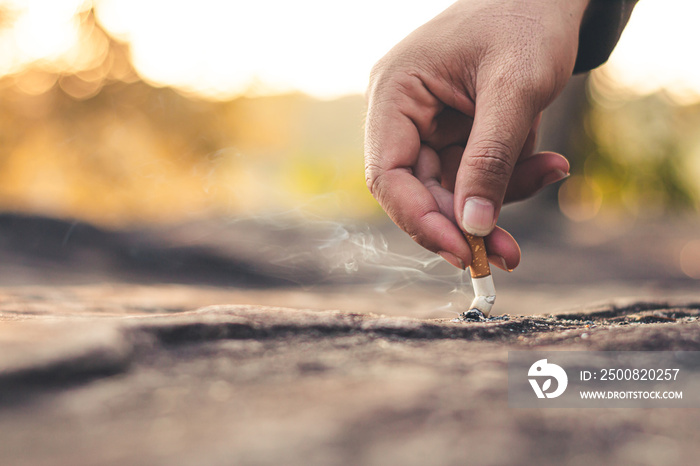 Men hand caught a burning cigarette causing smoke, concept stop smoking.