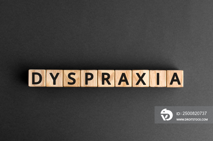 Dyspraxia - word from wooden blocks with letters, difficulties with physical movement and memory, dyspraxia concept, gray   background