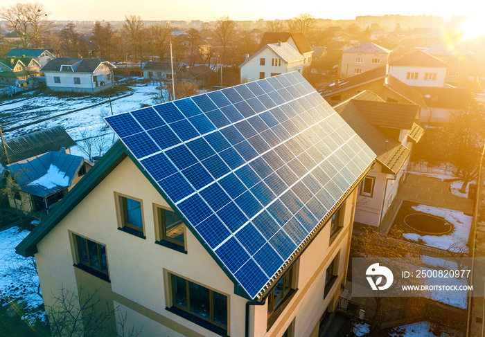 Aerial top view of new modern residential two story house cottage with blue shiny solar photo voltaic panels system on roof. Renewable ecological green energy production concept.