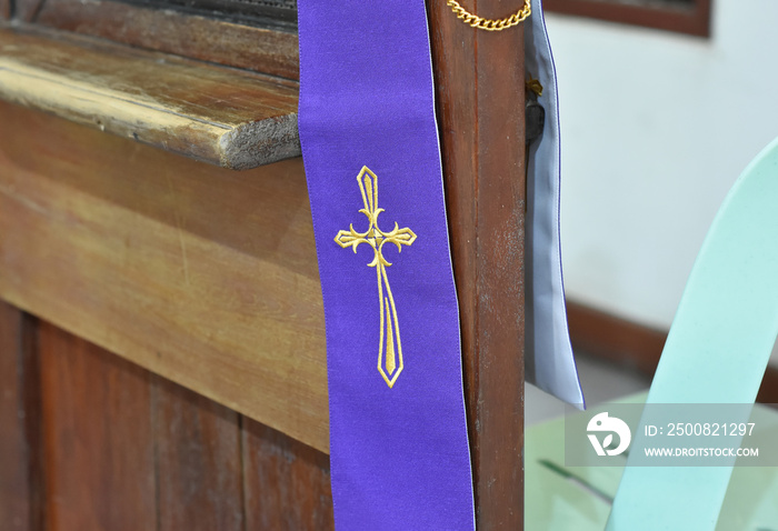 A cross symbol on a purple cloth for the priest is placed on a wooden platform for the confession of sins in Christianity.