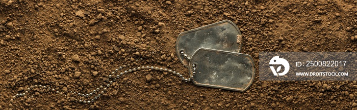 Lost US military soldier’s dog tags, rough and worn with blank space for text, covered in dirt. Memorial Day or Veterans Day concept.