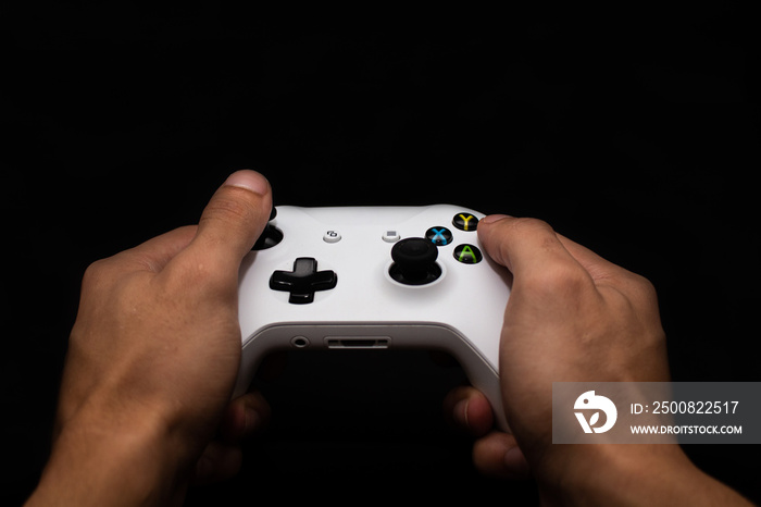 Man playing video games, holding control in hand with black background. Banner for video games and games with space for text.