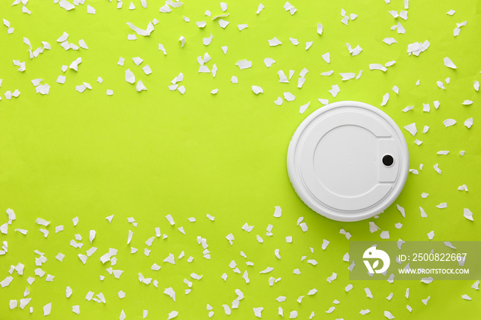 Modern robot vacuum cleaner and torn paper pieces on green background