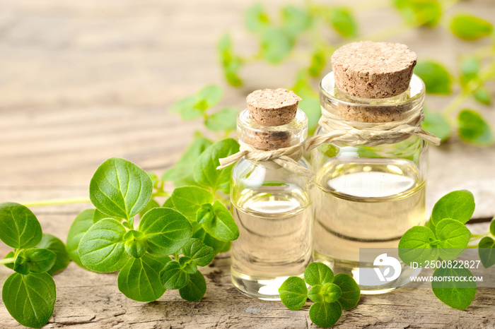 Oregano oil and fresh oregano leaves on the wooden table