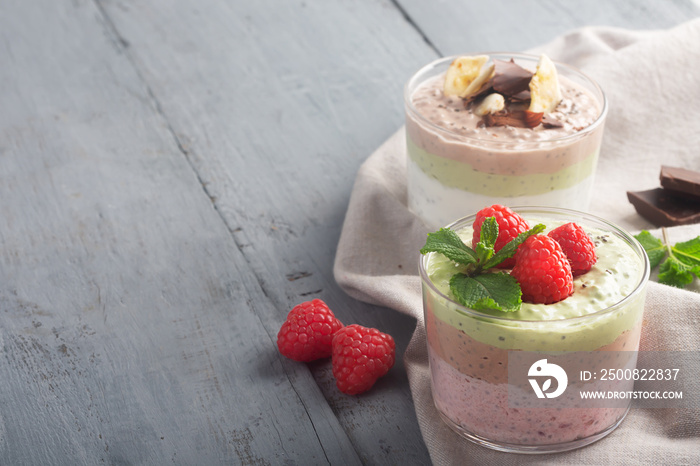 Chia seed pudding with three flavors, cocoa, matcha and strawberry with yoghurt, chocolate and mint leaves. Copy space