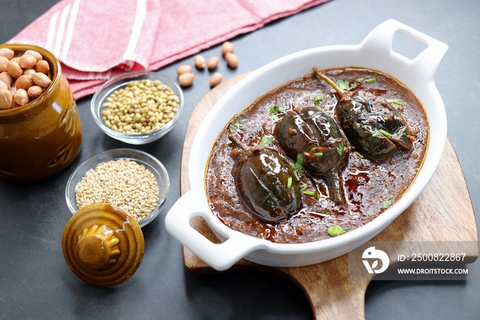 Brinjal curry. Baingan Masala or eggplant curry is a popular dish from India served in a white bowl. along with cooking ingredients and spices. copy space. Also known as Vangyachi bhaji in Marathi.