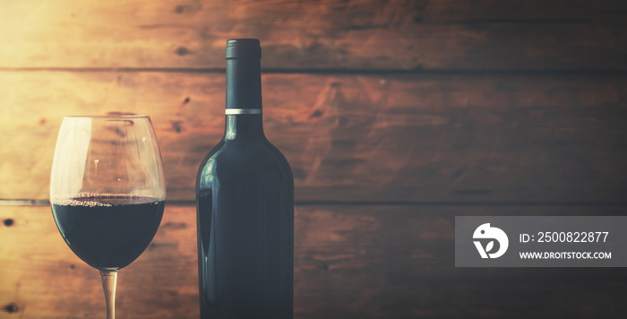 red wine bottle and glass on old wooden background with copy space