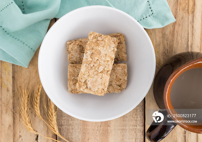 Wheat breakfast cereal raw in bowl on rustic wooden table - top view photograph