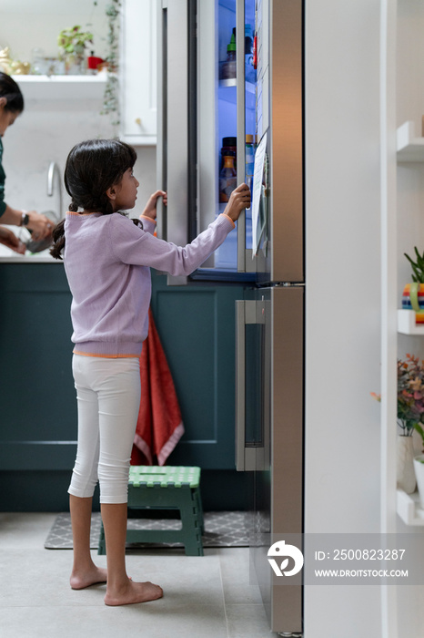 Little girl opening fridge