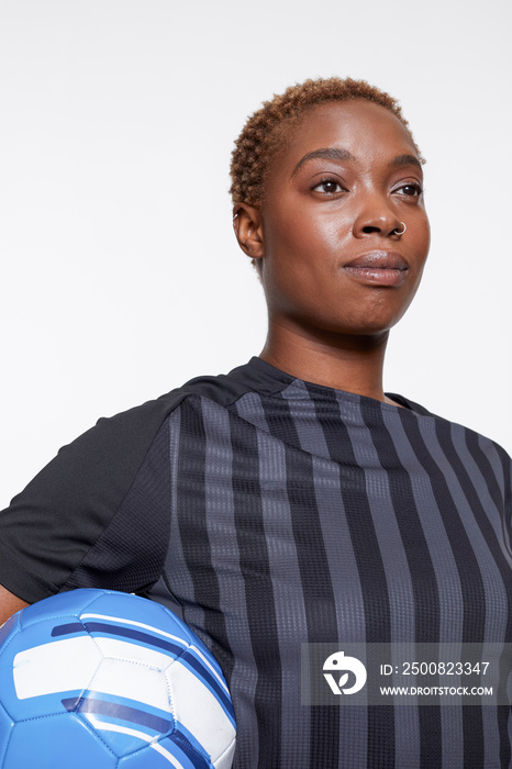 Studio portrait of female soccer player with ball