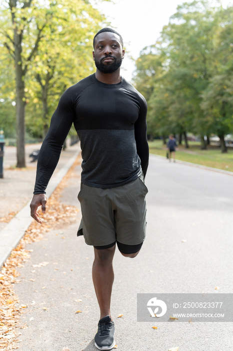 Portrait of athletic man stretching leg in park