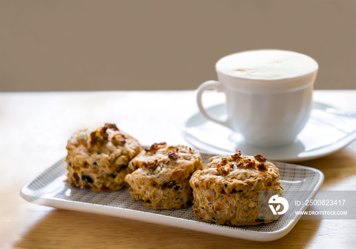 Traditional British cheese scones with blurry cup of coffee and  book background, freshly baked scones english buns with bright light morning  or afternoon tea in spring or summer in tea room