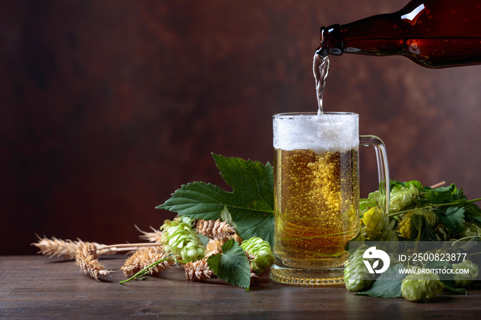 Mug of beer, grain and hops on a old wooden table.