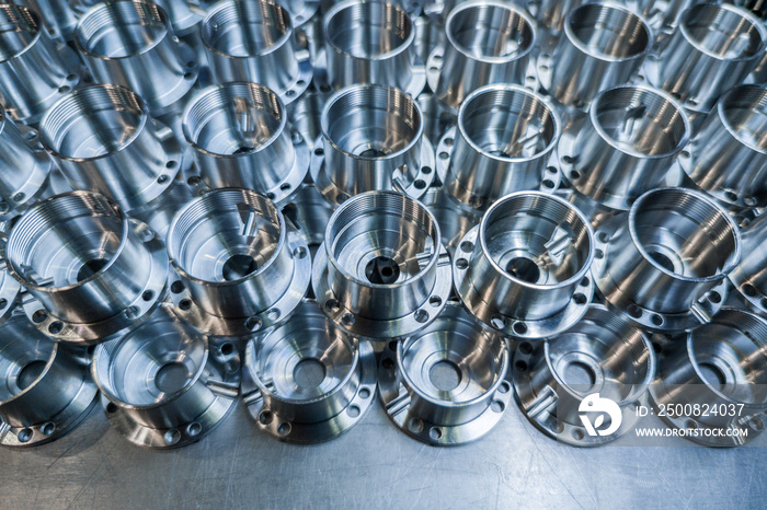 a batch of shiny aluminium aerospace parts made with cnc machine - close-up with background blur, industrial backdrop