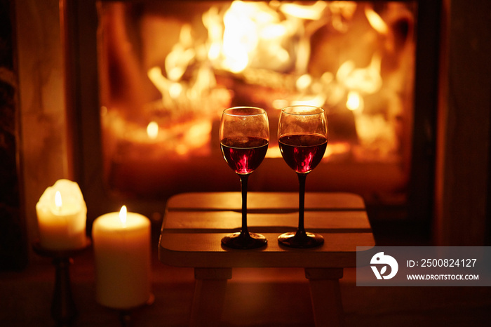 Two glasses of red wine near fireplace