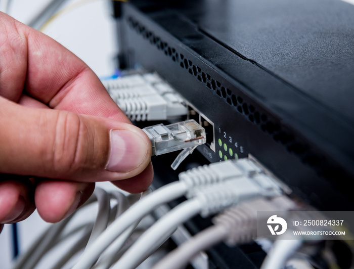 Technician connecting network cables to switches. Connecting cables in server cabinet.