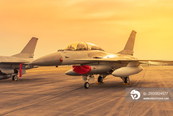 military fighter jet aircraft parked on runway in the base airforce standby ready to take off for military mission on sunset