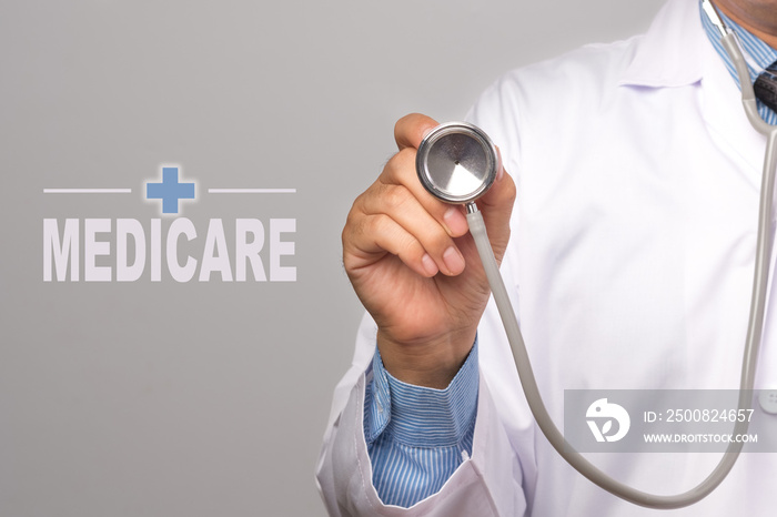 Doctor holding a stethoscope and word  MEDICARE  on gray background. concept Healthy.