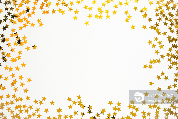 Golden confetti in the form of stars isolated on white background. Festive day backdrop. Flat lay style with minimalistic design. Template for banner or party invitation