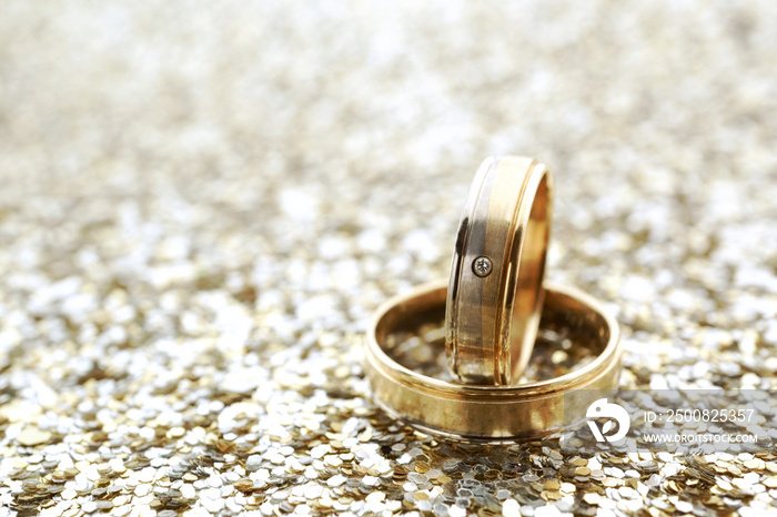 Gold wedding rings on glitter background with copy space