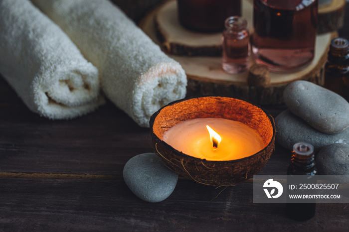 Concept of natural essential organic oils, Bali spa, beauty treatment, relax time. Atmosphere of relaxation, pleasure. Candles, towels, dark wooden background. Alternative oriental medicine