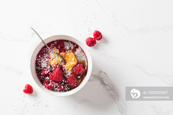 Chia pudding in bowl with raspberries, peanut butter and coconut. Vegan food concept.