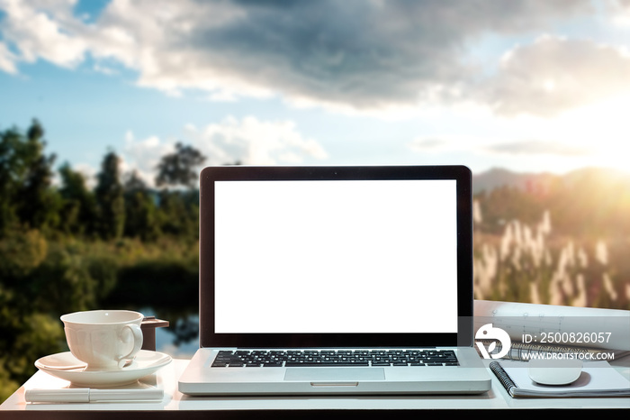 Front view of cup and laptop on table in Office Mountain and background of trees in the forest