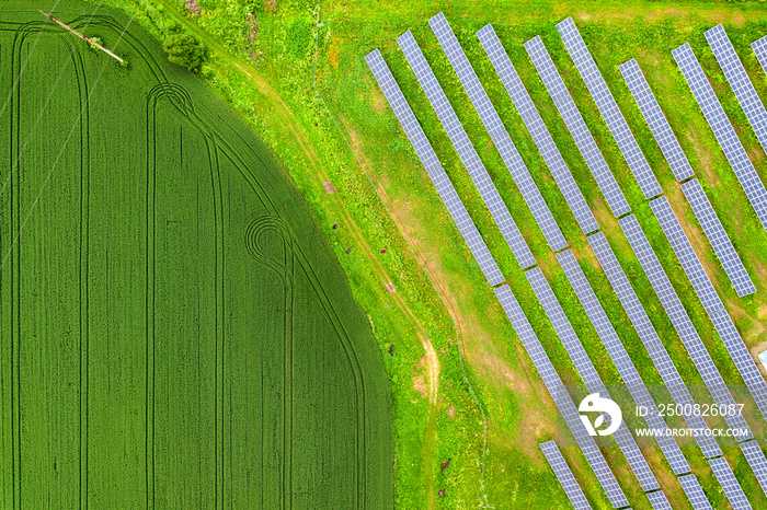 Aerial view of solar power plant on green field. Electric panels for producing clean ecologic energy.